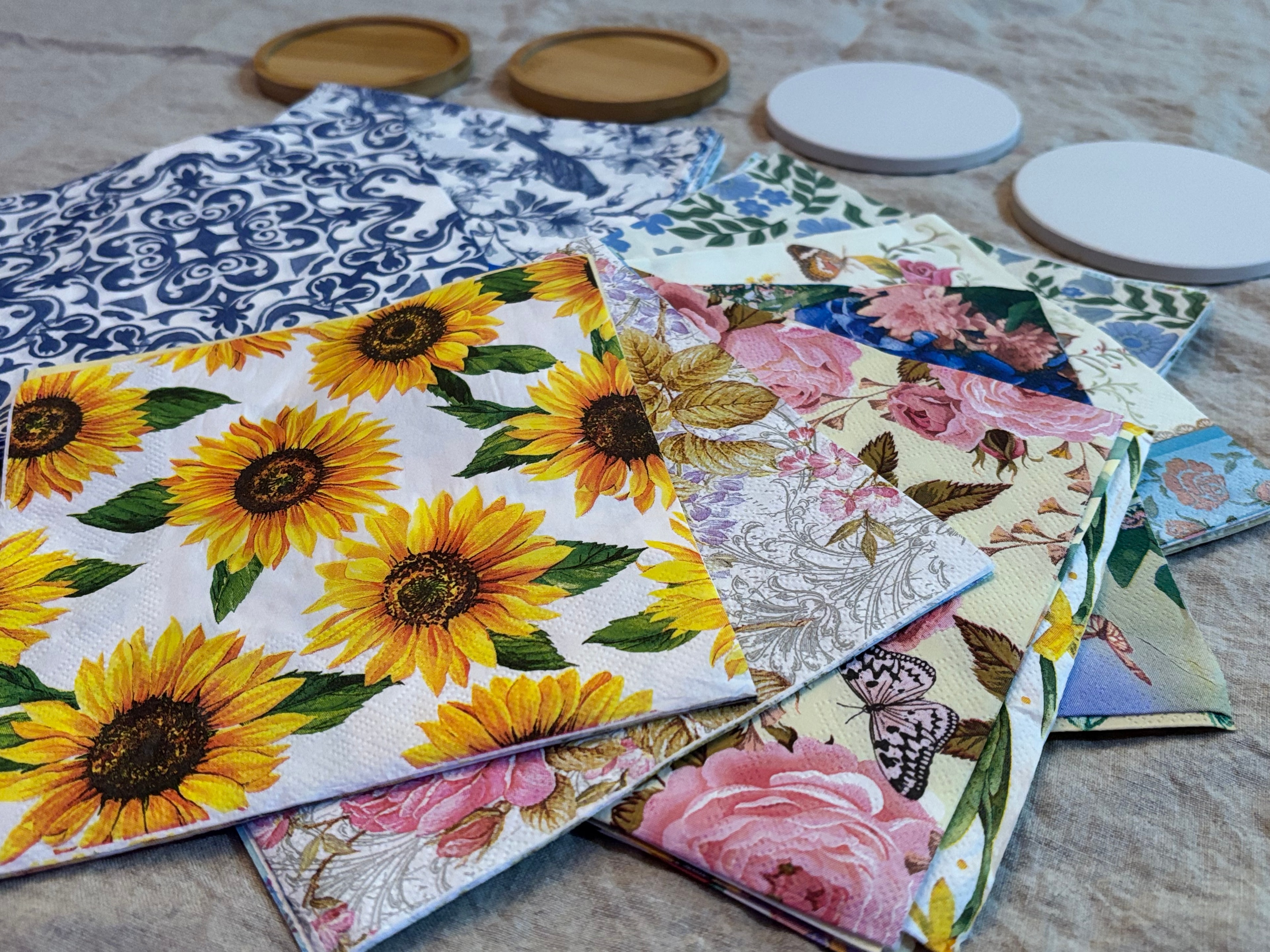 Floral decoupage napkins with sunflowers, roses, and botanical prints alongside wooden coasters