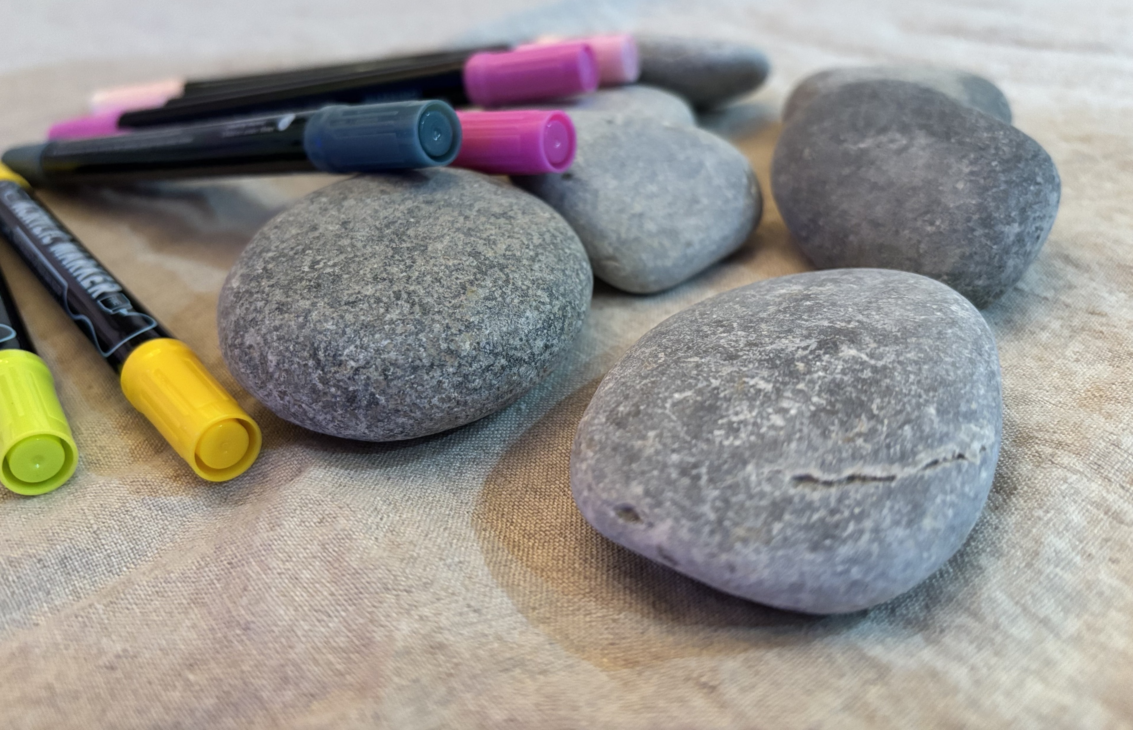 Smooth stones and colorful markers laid out for a rock painting project