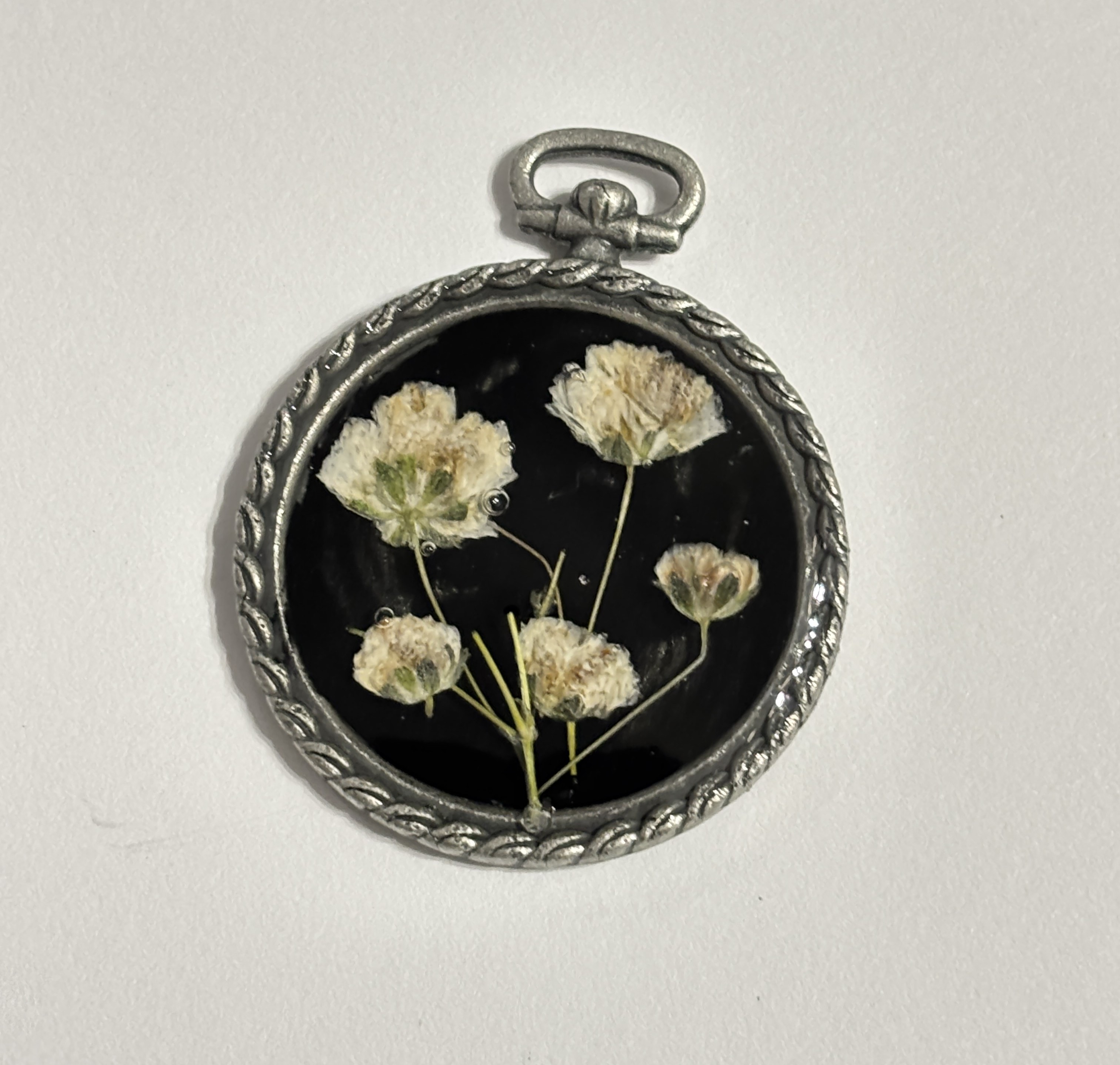 Pressed wildflowers in a round silver pendant frame